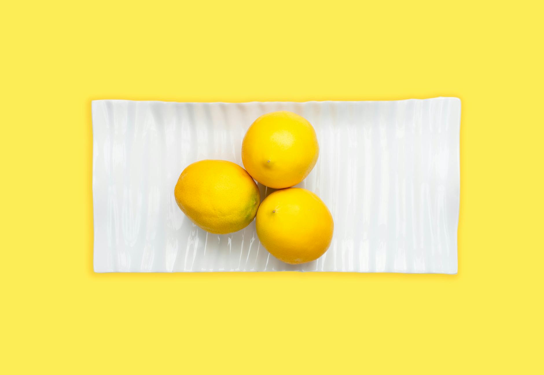 Fresh lemons on a white plate with yellow background symbolizing vitality and renewal