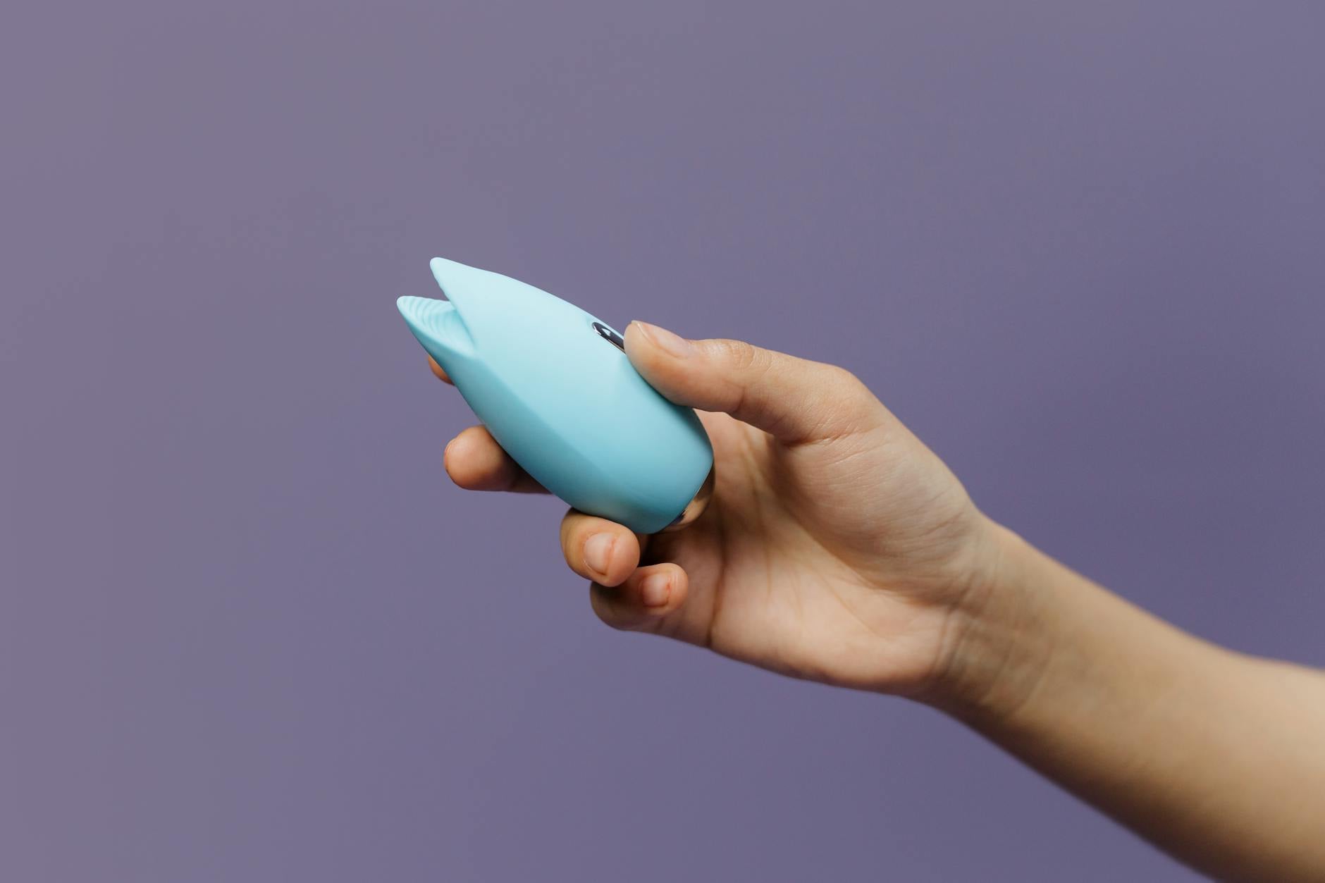 A silicone vibrator held in hand, representing introducing pleasure devices to a new partner with confidence