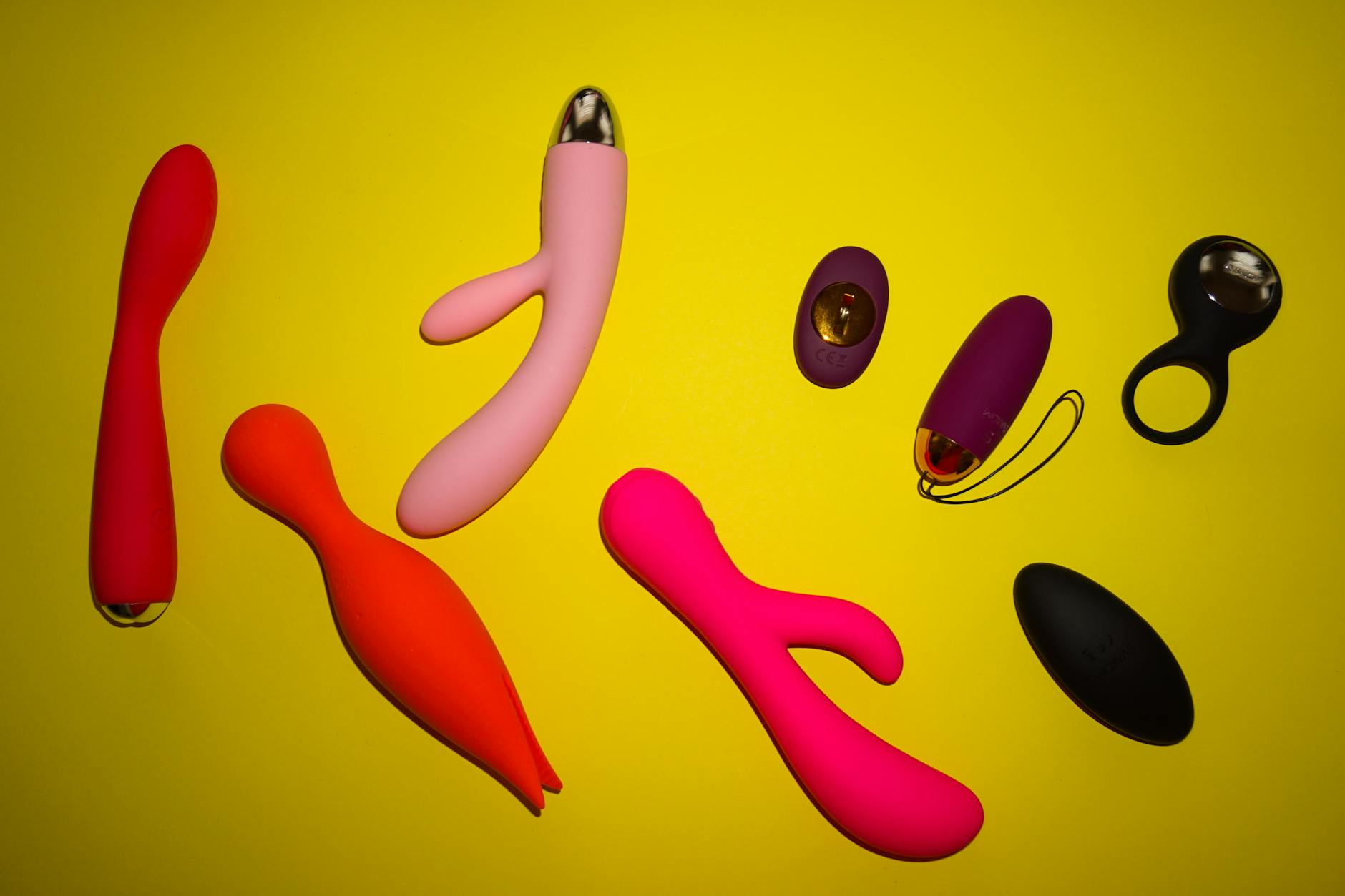 Colorful vibrators arranged on a bright yellow background, representing diverse pleasure tools and gentle exploration